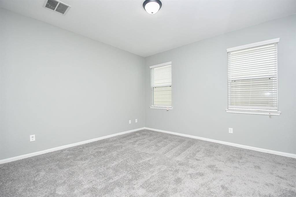 This spacious secondary bedroom downstairs offers versatility, whether used as a guest room, office, or personal retreat. Large windows bring in natural light, while the soft gray palette and plush carpeting create a soothing atmosphere.