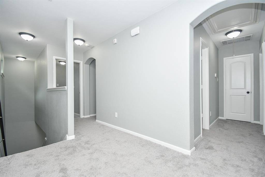 A soft, neutral palette and plush carpeting give the upstairs landing a welcoming feel. Multiple archways lead to the surrounding bedrooms, keeping the space open and airy.