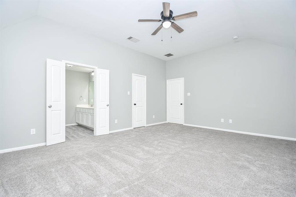 This view showcases the bedroom’s generous proportions, with double doors leading to the en suite bath.