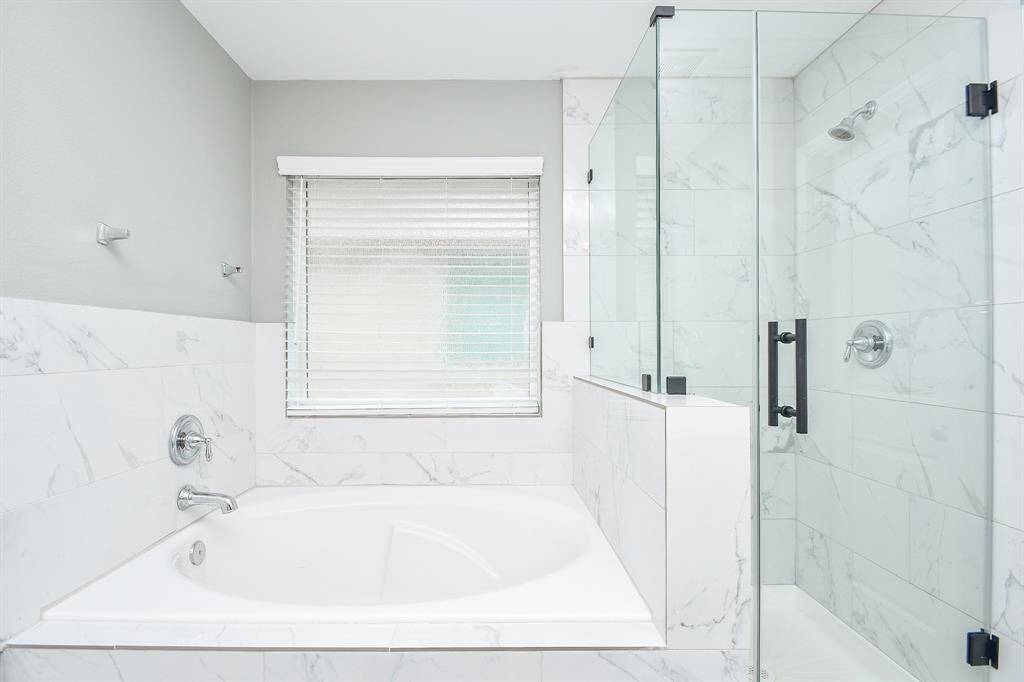 From this angle, the luxurious soaking tub and separate glass-enclosed shower come into focus. The thoughtful layout balances practicality with comfort, making this bathroom a standout feature of the home.