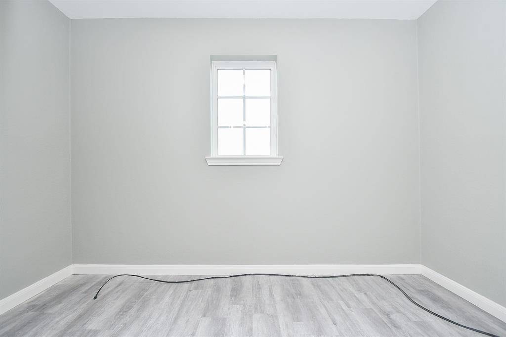 A small window adds a touch of natural light to this storage room, making it more than just a tucked-away space. Shelving or bins could be added to maximize organization.  Its placement near the laundry room adds to its convenience.