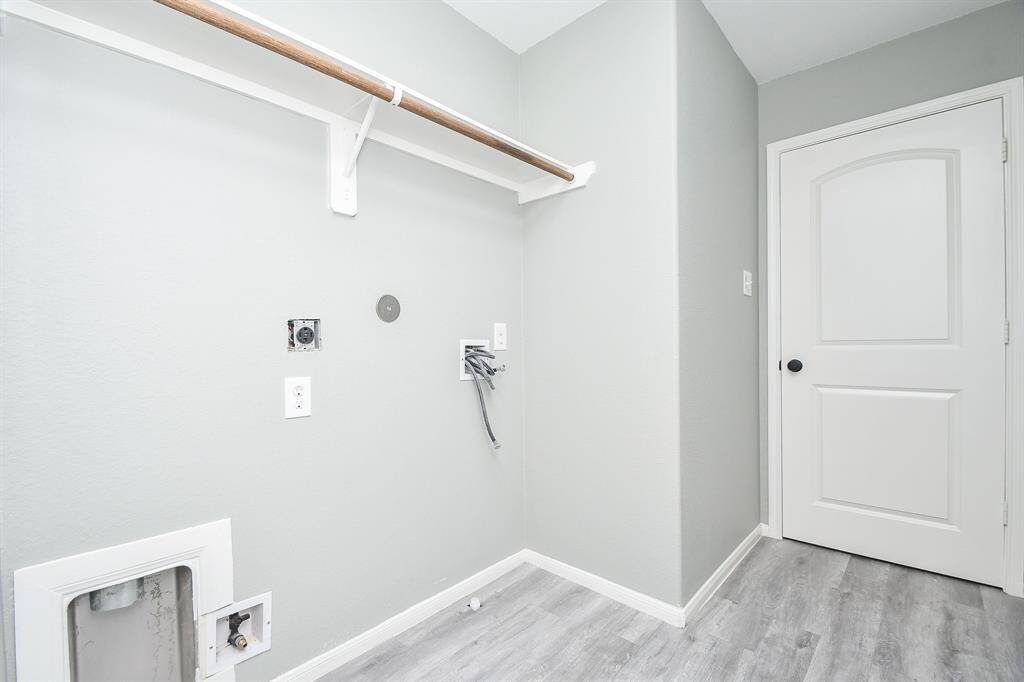 This well-sized laundry room provides ample space for a washer and dryer, with an overhead rack for added storage. A practical setup keeps the area neat and efficient.
