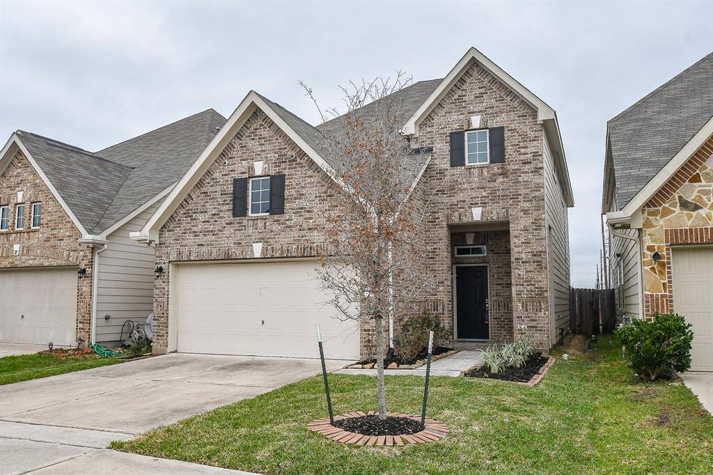 From this angle, the home’s distinct entrance comes into focus, set back through an open archway that creates a semi-enclosed feel. The covered entry adds an element of privacy and shelter before reaching the front door.