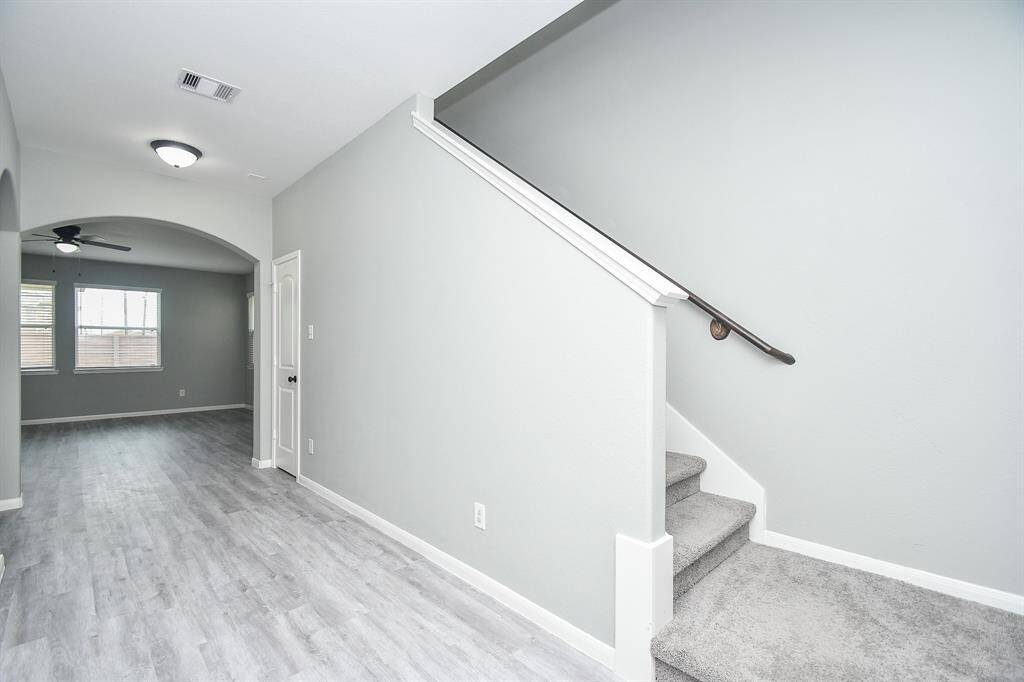 Step inside to a bright and open entryway that reveals its connection to the rest of the home. Carpeted stairs rise to the upper level, creating a focal point as soon as you walk in. A wide archway frames the view ahead, leading into the spacious living area.