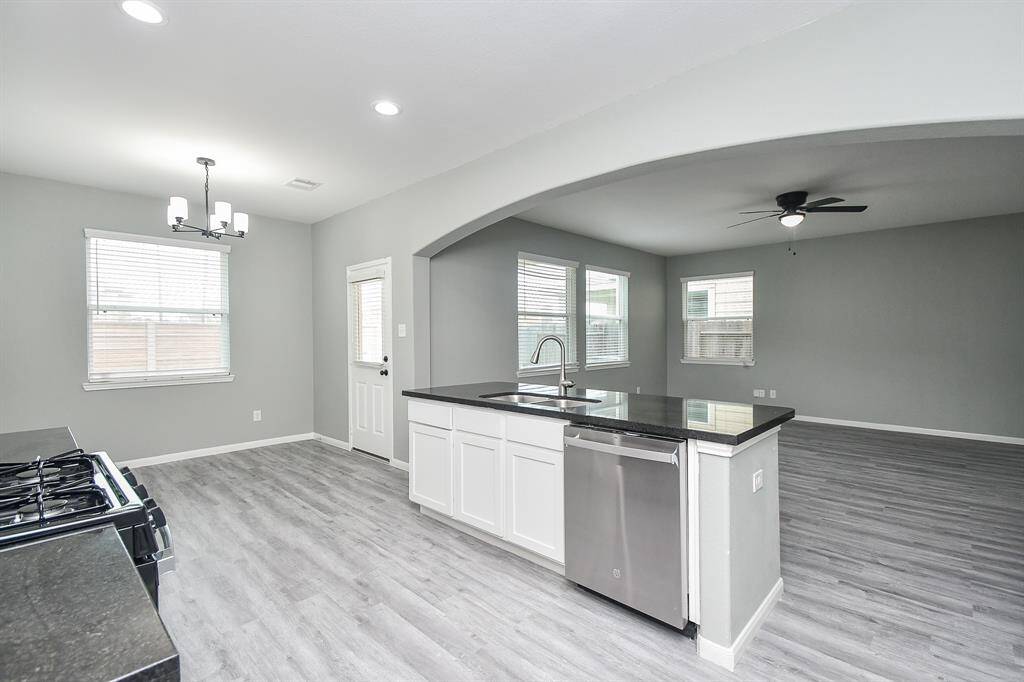 This perspective highlights the kitchen’s seamless flow into the adjacent dining area, which sits beside large windows that invite in natural light.