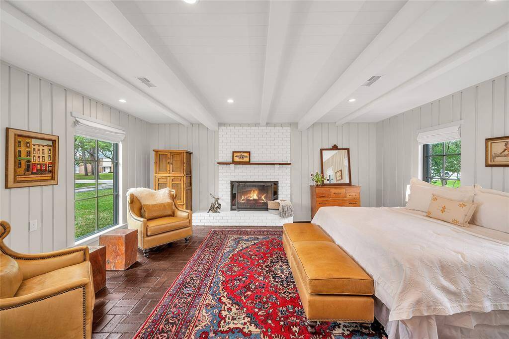 Irresistibly Serene Setting...one of two primary en-suite bedrooms, featuring distinctive original brick flooring and a gas & wood burning fireplace, creating a cozy ambiance