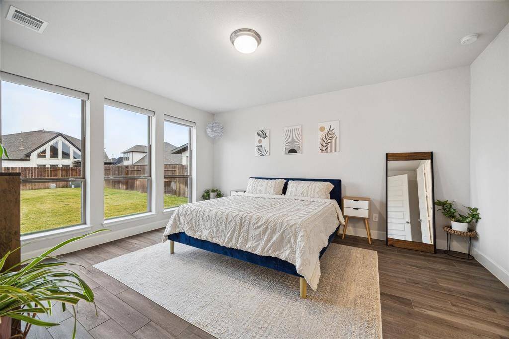 Bright and spacious Primary suite with large windows overlooking the oversized fenced backyard. Upgraded wood-like tile flooring, modern blackout shades, and ample natural light.