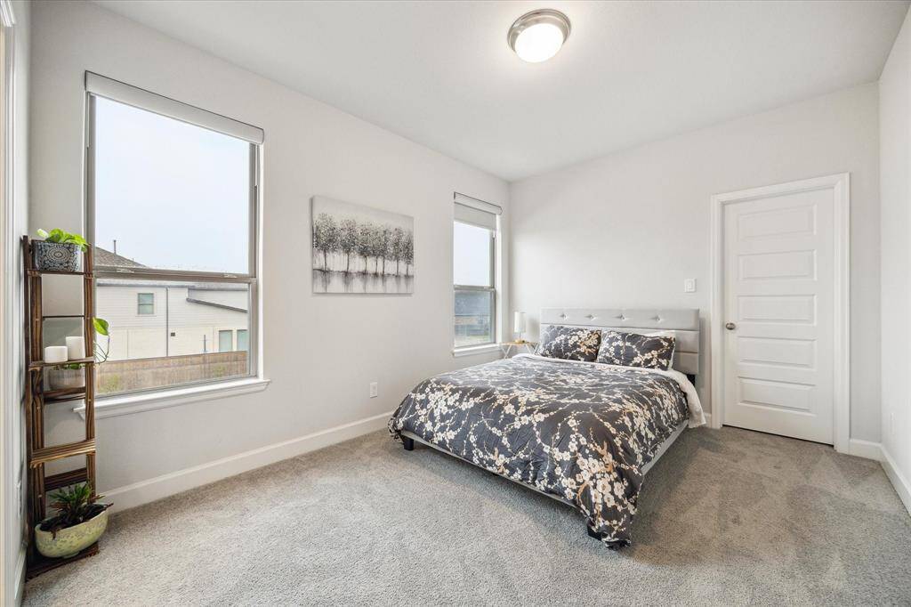 Bright bedroom with large windows, neutral walls, and carpeted flooring. This bedroom has its own private bathroom.