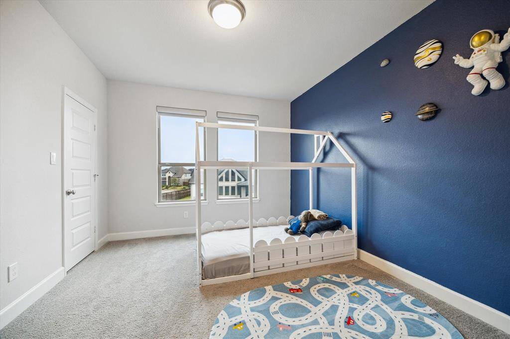 This secondary bedroom features a playful space theme with a blue accent wall and soft carpet. Easy access to the Jack and Jill bathroom.  The bedrooms also have blackout shades.