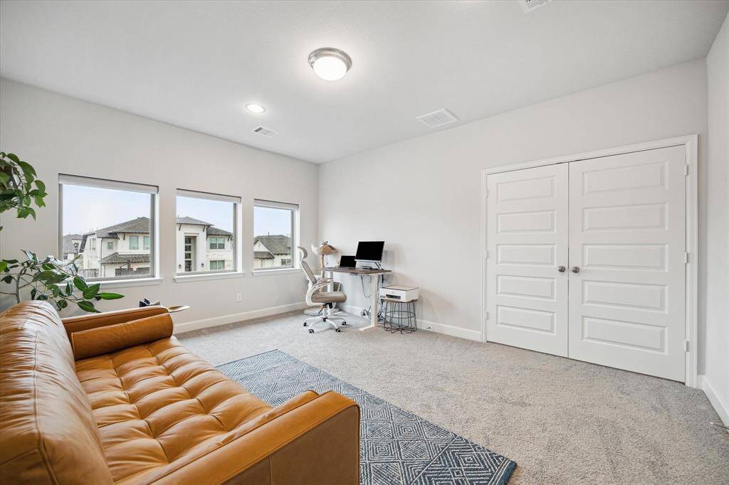 The Media room has double doors, and is currently being used as an office.  It is also bright and spacious with three large windows offering plenty of natural light. It features a modern design with neutral walls. The carpeted floor adds warmth.