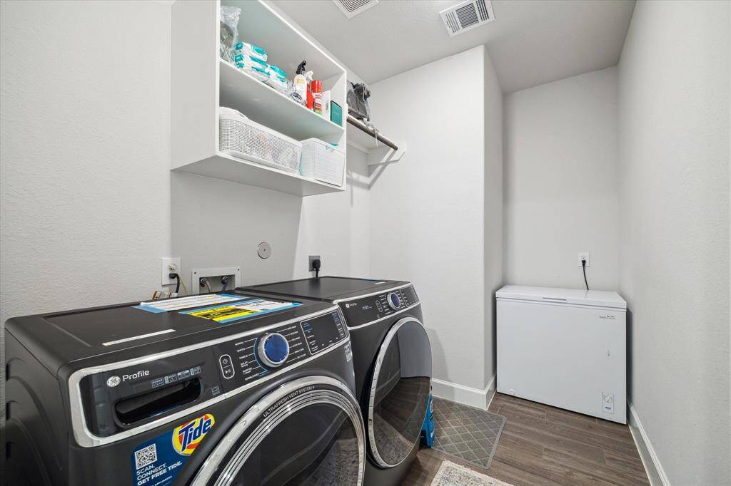 The spacious laundry room has open shelving for storage and is well-lit!  The lovely washer and dryer can be included.  Perfect for efficient household chores.