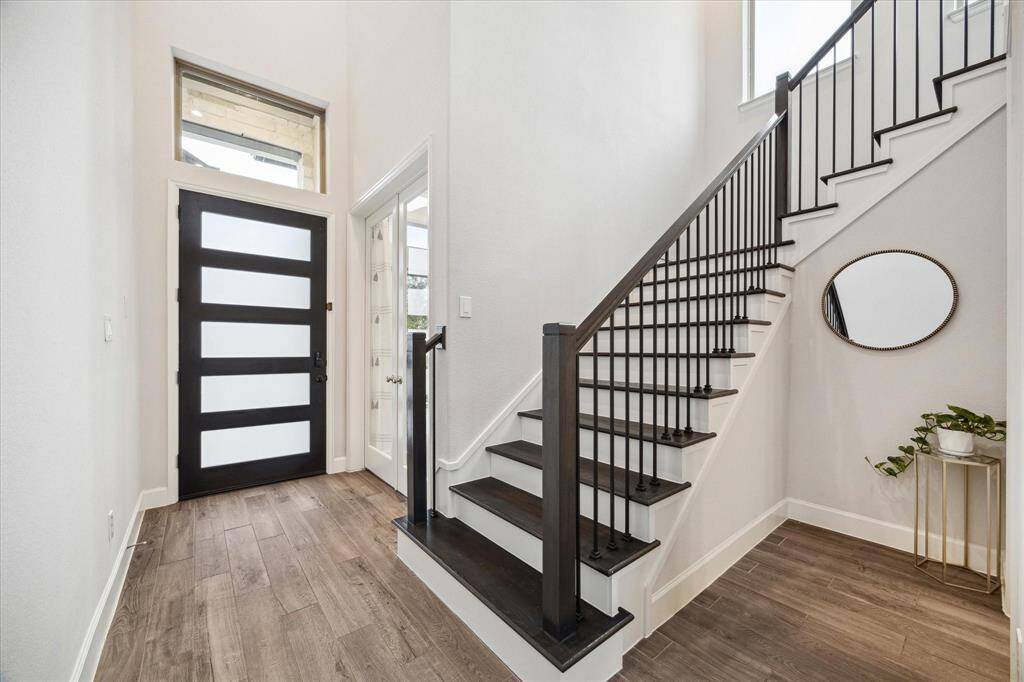 Step into the inviting entryway elegantly framed with the sophisticated home office with French doors and a graceful staircase, setting the tone for timeless style and comfort.