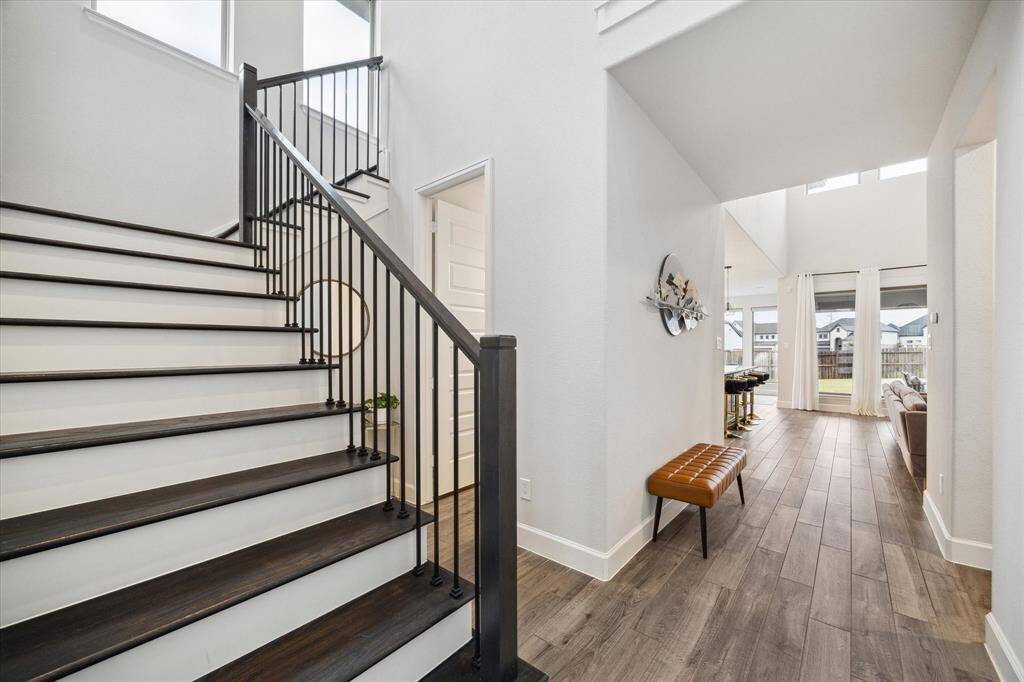 The front entrance showcases a stunning upgraded staircase with Red Oak hardwood treads and elegant wrought iron spindles, adding a touch of timeless charm.