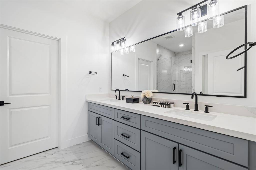 With soft gray cabinetry, quartz countertops, and chic black hardware, this bathroom combines sophistication with functionality.