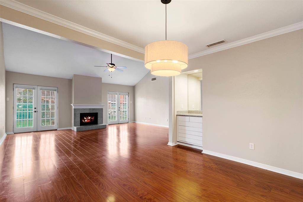 Dining room offer a built-in wet bar area, perfect for entertaining. The room is finished with a neutral color palette, crown molding, and a modern pendant light fixture.