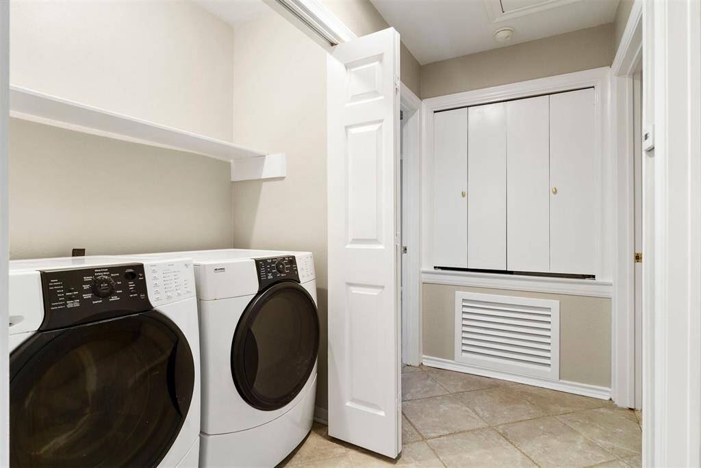 This is a dedicated laundry space with a washer and dryer set, ample overhead shelving for storage.