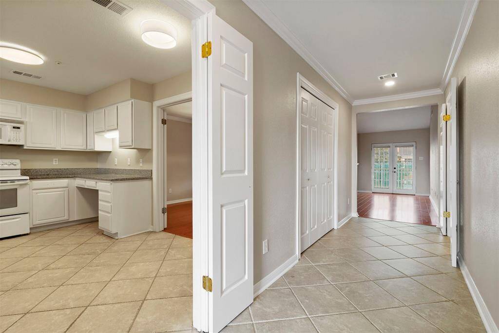 Open-concept home with a spacious kitchen leading to a living area with tiles. There are French doors at the far end, suggesting access to outdoor space.