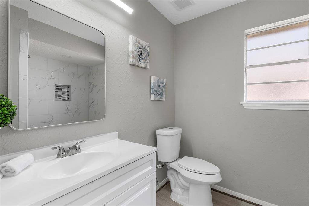 Remodeled Primary bathroom with new vanity, lighting, shower, flooring and toilet.
