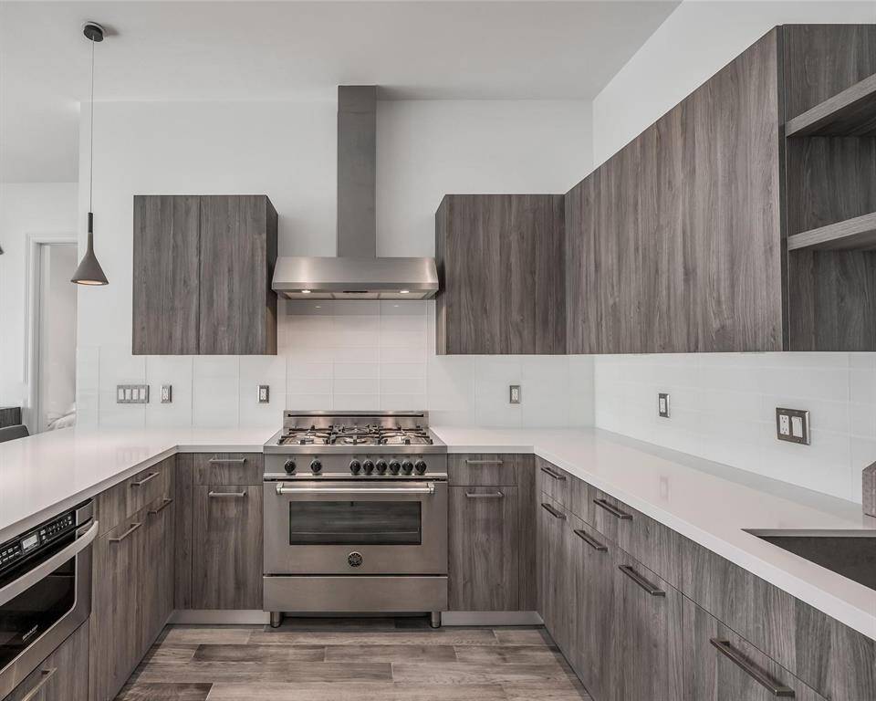 A closer view of the kitchen showcases the large, expansive countertop, perfect for meal prep and entertaining. The high-end stainless steel appliances offer both style and functionality, while the sleek backsplash adds a modern touch, tying the whole space together with elegance.