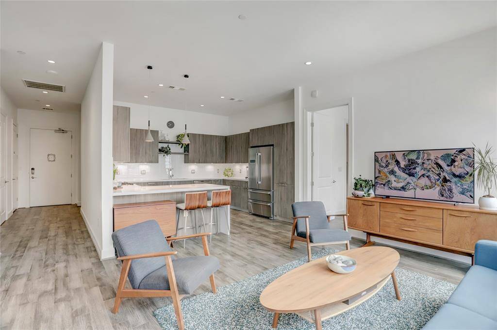 From this vantage point, you can appreciate the open flow of the living area, with the kitchen visible ahead and the foyer to the left. To the right, a door leads to the tranquil primary bedroom, offering privacy and a peaceful retreat.