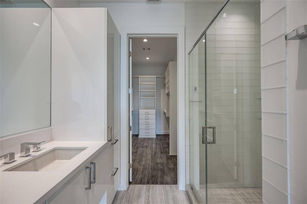 As you approach the walk-in closet, you'll notice the beautifully crafted built-in cabinetry, offering both style and practicality for all your storage needs. To the right, a glass door leads to the sleek walk-in shower, adding a touch of elegance and modern design to the space.