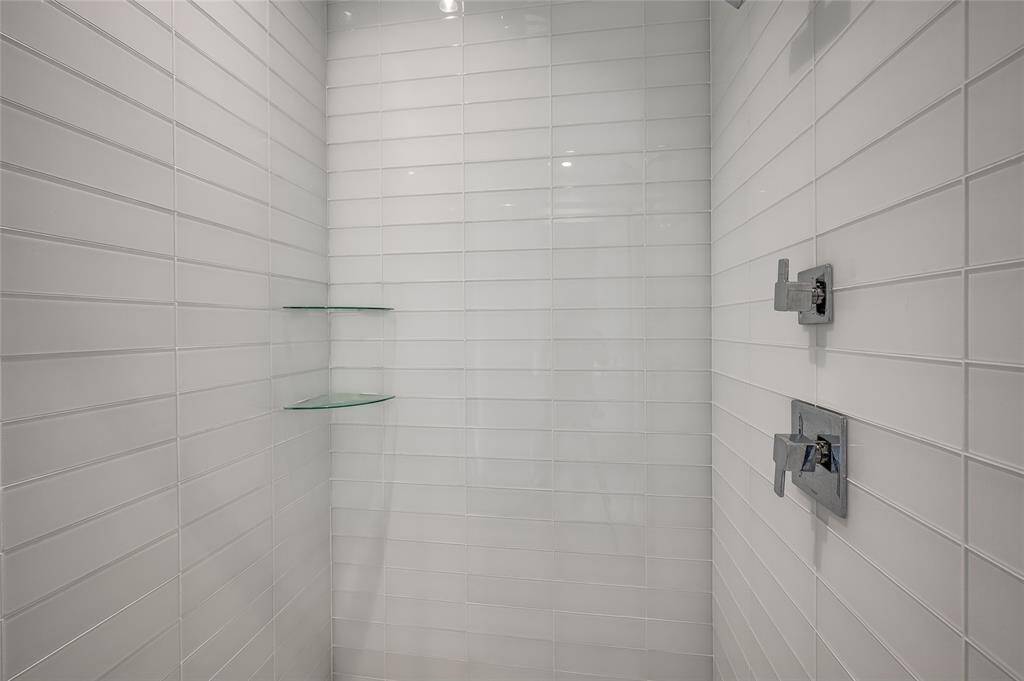 Sleek, contemporary tiles adorn the walk-in shower, creating a clean and stylish look. The polished design enhances the space, offering a luxurious and modern feel.