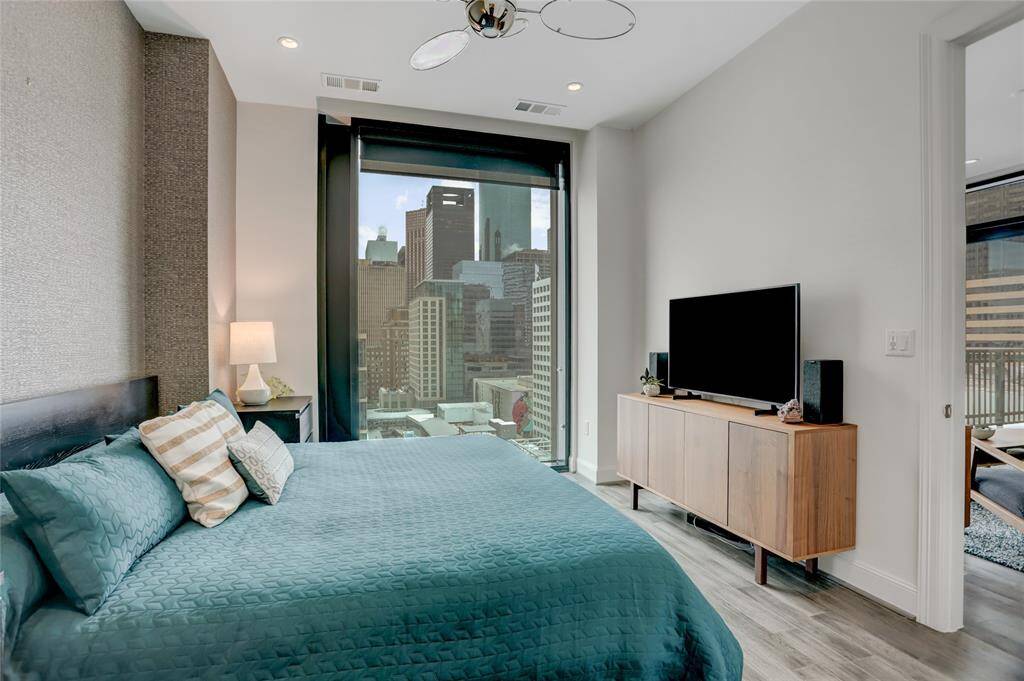 Another view of the primary bedroom highlights its spacious layout and inviting atmosphere. Stunning views of the surrounding skyscrapers, bringing the energy of the city into the room while maintaining a peaceful ambiance.