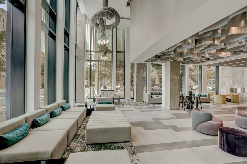 A mix of plush seating and artistic accents offer a comfortable yet striking environment, perfect for casual meetings or a moment of relaxation. Floor-to-ceiling windows bring in natural light, enhancing the open, airy feel.