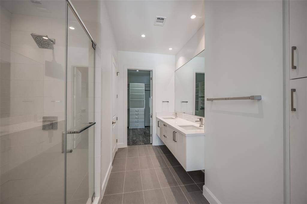 The expansive primary bathroom offers a luxurious experience with a floating quartz vanity and double sinks. Ample cabinet and drawer space ensure plenty of storage, while the desirable walk-in shower adds an elegant touch. The oversized closet provides even more room for organization, making this space as functional as it is beautiful.