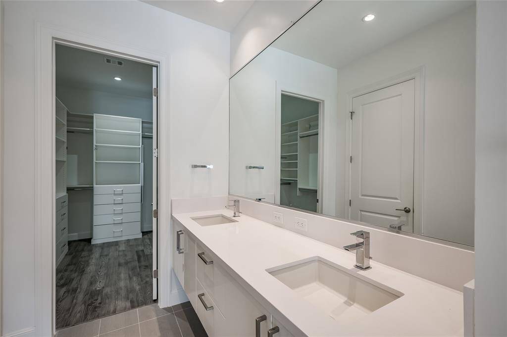 A closer look at the stunning floating double vanity, elegantly positioned to lead you into the spacious walk-in closet. The sleek design of the vanity complements the modern aesthetic of the bathroom, creating a transition to the expansive storage space beyond.