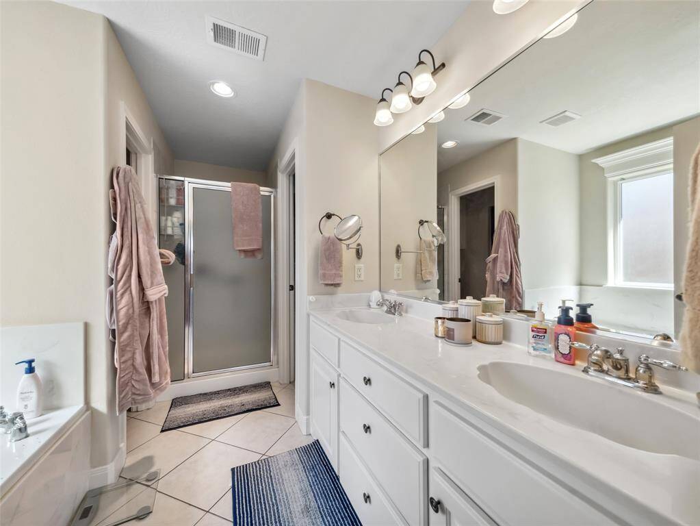 Primary bath with double sinks, separate shower and toilet room. Vanity has plenty of storage space.