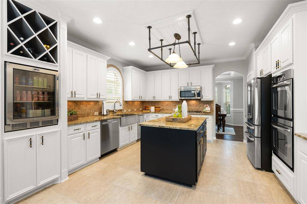 WOW! Where do I start with this stunning, professional grade Kitchen? Beautiful granite counters, comfort-height TRUE brand wine-fridge, tumbled tile backsplash with under-cabinet lighting, and 2-tone cabinetry: white perimeter storage with a Tricor Black center island.
