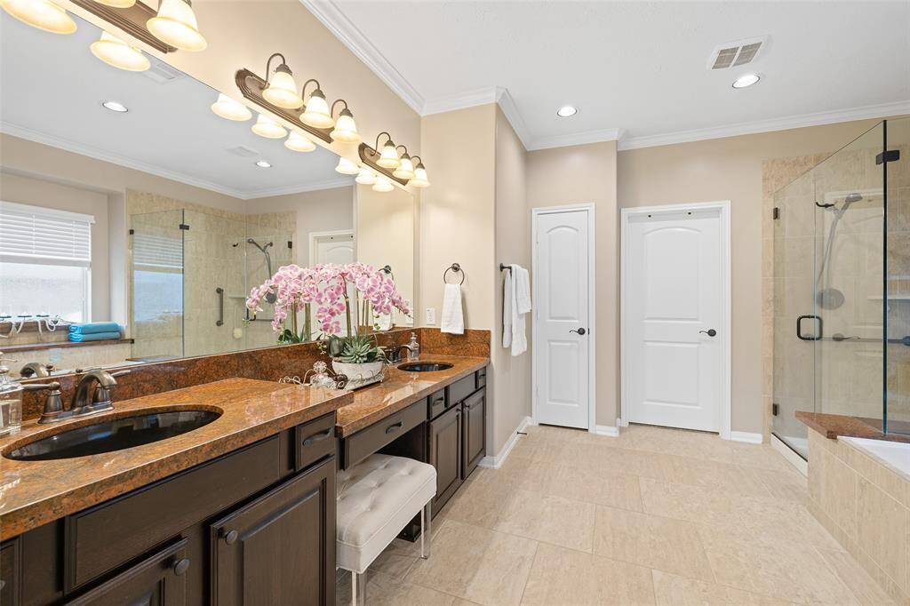 Your Primary Bath offers two undermounted sinks, dual-height vanity with sitting area, luxurious granite counters, rich wood cabinets and a full-width mirror. Oil rubbed bronze plumbing fixtures, lighting fixtures and hardware work beautifully with the neutral walls and tile floors. A private WC provides discretion during the busy morning rush. There is also a deep linen closet and LARGE walk-in closet with customized storage system.