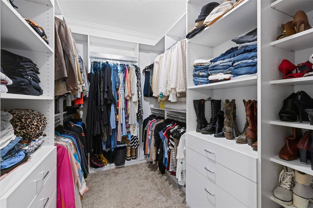 The oversized walk-in closet has been outfitted by California Closets. This customized storage system provides plenty of room for two, including variable height hanging rods, and two storage towers with adjustable open storage and 4 drawers per side.