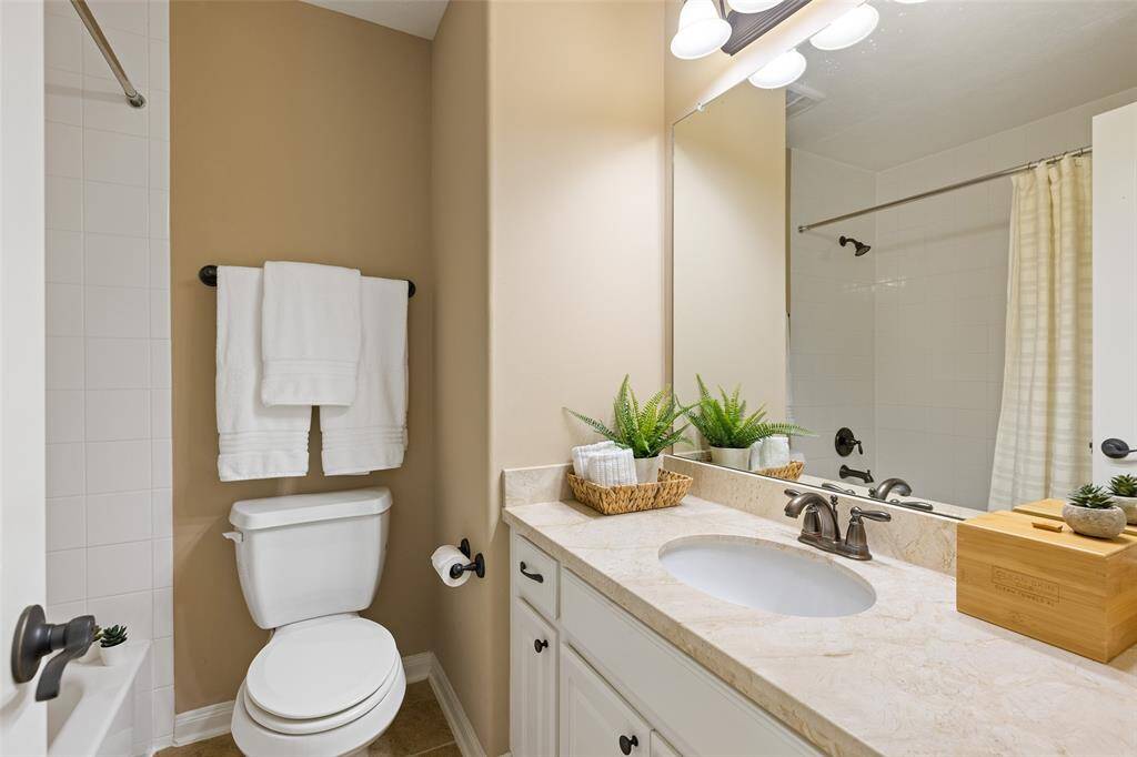 The upstairs hallway Bathroom includes a white-tiled combination tub & shower, extra wide granite vanity with recessed sink, cabinet storage, a full-width mirror along with oil rubbed bronze hardware, lighting and plumbing fixtures.
