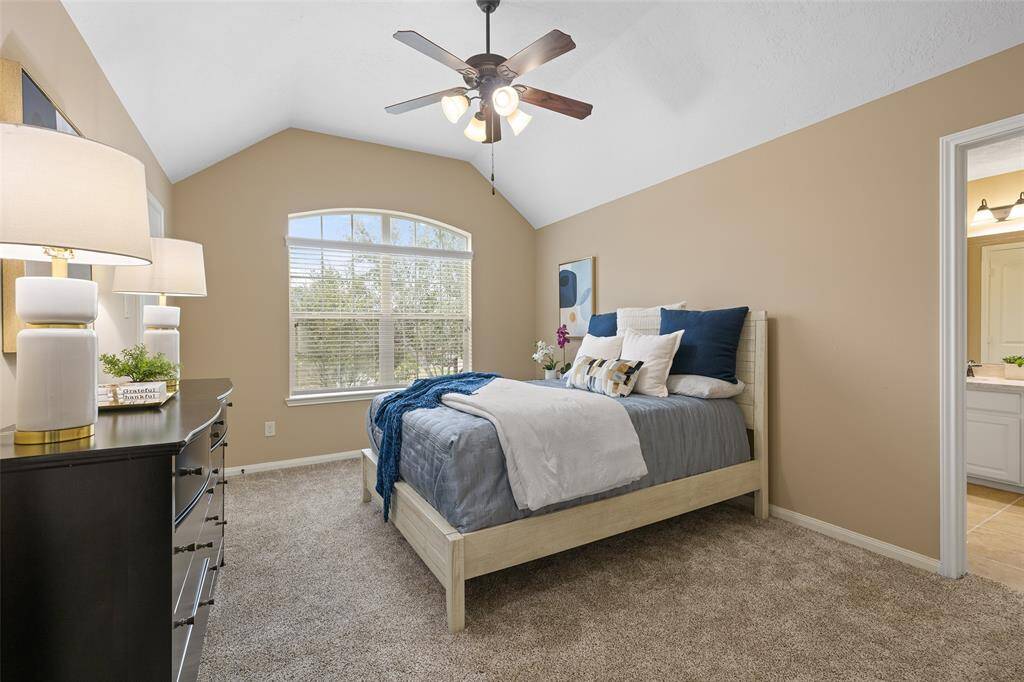 Secondary Bedroom #3 is another large room, measuring 14’ x 11’ with a 10’ vaulted ceiling, fan, carpet and walk-in closet. Notice the tree-top view of the front yard.