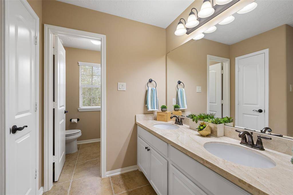 Shared between Bedrooms 3 and 4, this Jack & Jill Bathroom offers a linen closet and granite topped vanity with two recessed sinks, full-width mirror and cabinet storage. The private WC includes a combination tub and shower with white tile extended to the ceiling. This is a fantastic, functional Bathroom layout for kids to share.