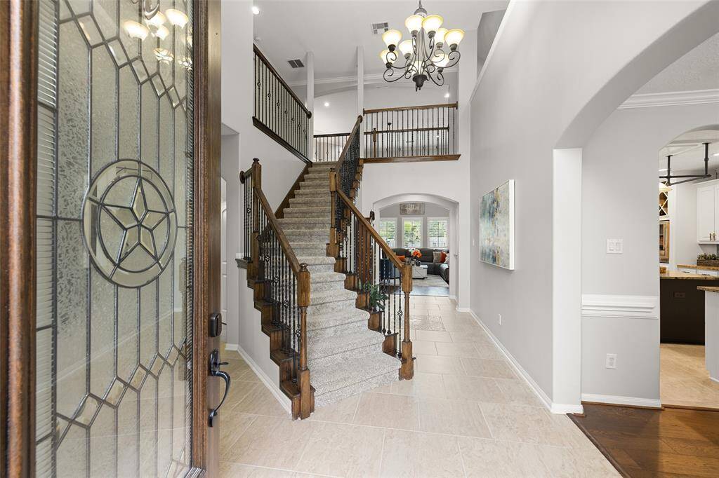 What an impressive first impression. The Foyer is GRAND, with a soaring 18’ ceiling, crown molding, 20’ square tile floors, decorative tile inlay, arched casement openings, oil rubbed bronze chandelier, beautiful hardwood door with leaded glass and Texas star accents, rich wood and wrought iron stairs and landing. There is SO MUCH to LOVE about this home.