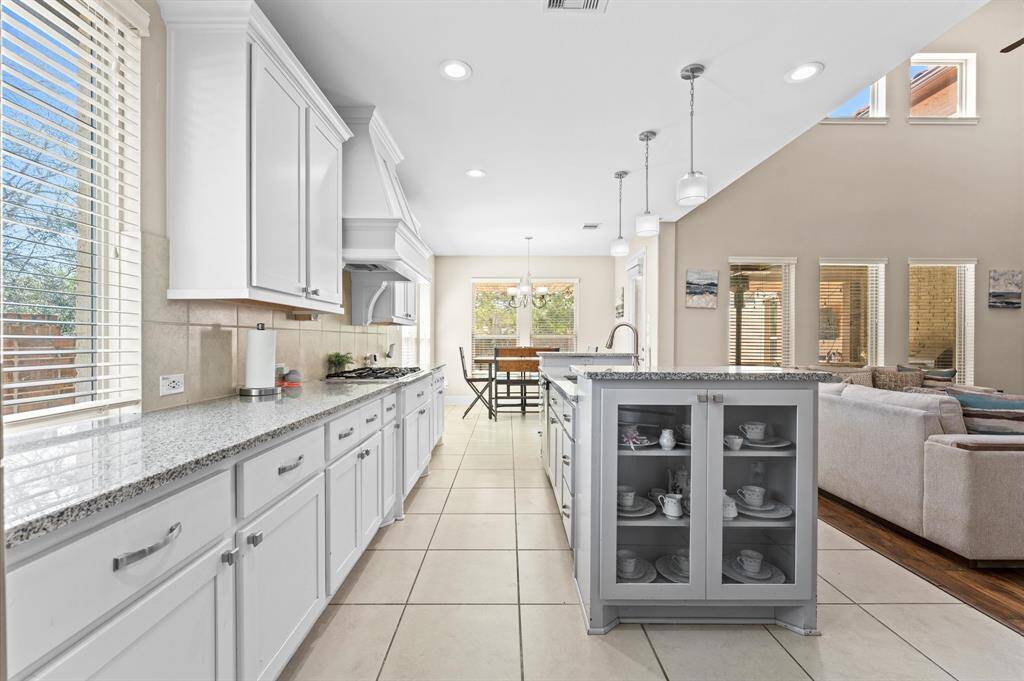 Sleek, white cabinets complement the bold, polished granite in this stunning kitchen.