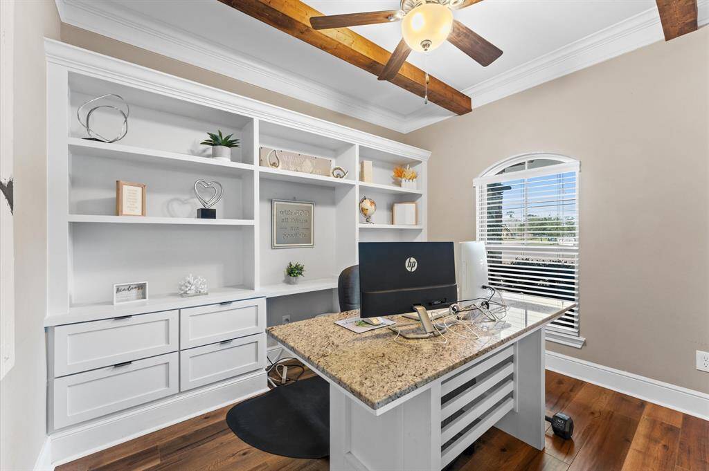 To the right of entry, you will find a thoughtfully designed home office. Complete with built-in shelves, drawers and work space/desk. The ceiling is adorned with wooden beams, adding a touch of rustic charm and character to the space.