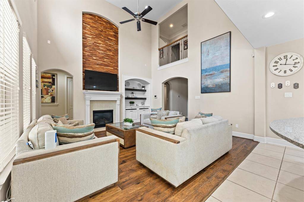 Two-story living room with a captivating focal point: the fireplace. Above the fireplace, the art niche is covered with striking wood panels; adding warmth and texture to the space, and draws your eyes upward toward the ceiling.
