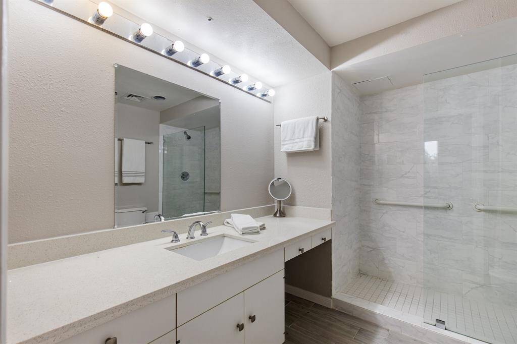 Primary bathroom with Quartz counters, vanity area and seamless glass walk-in shower.