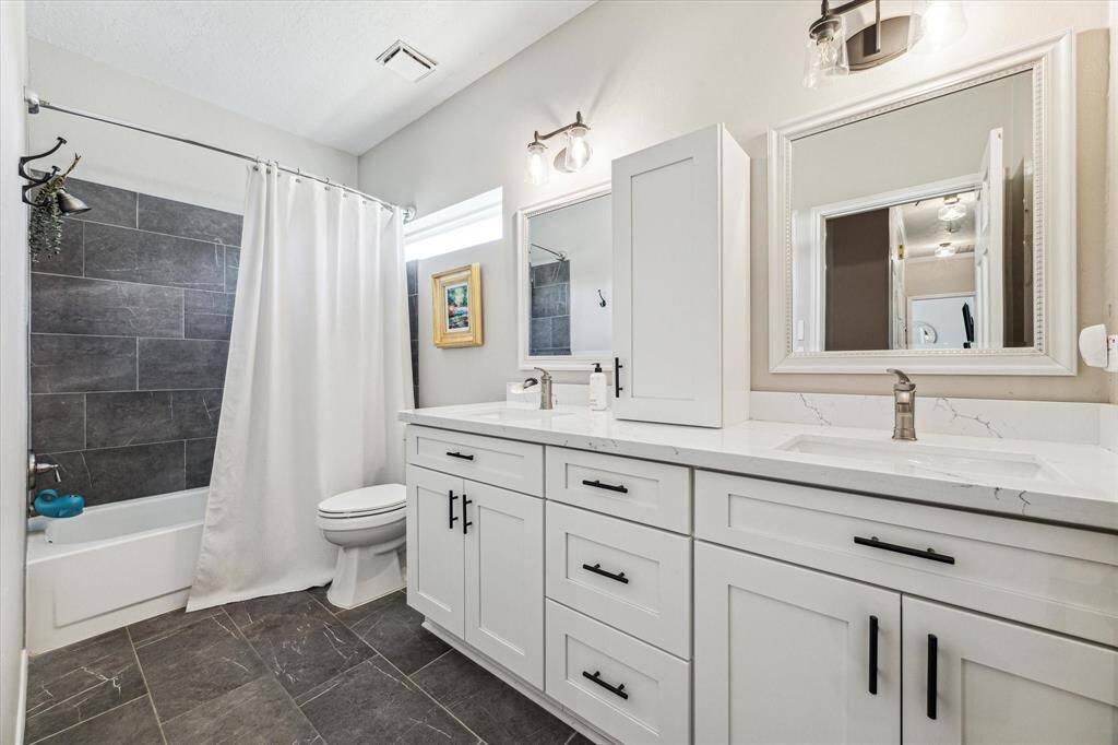 Experience the fully remodeled upstairs secondary bath, featuring dual sinks, ample cabinet storage, and a convenient tub/shower combo.