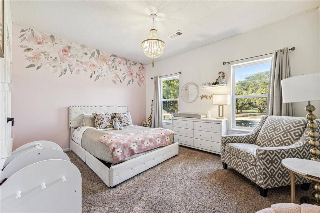 This charming upstairs bedroom features an elegant light fixture and is filled with natural light.