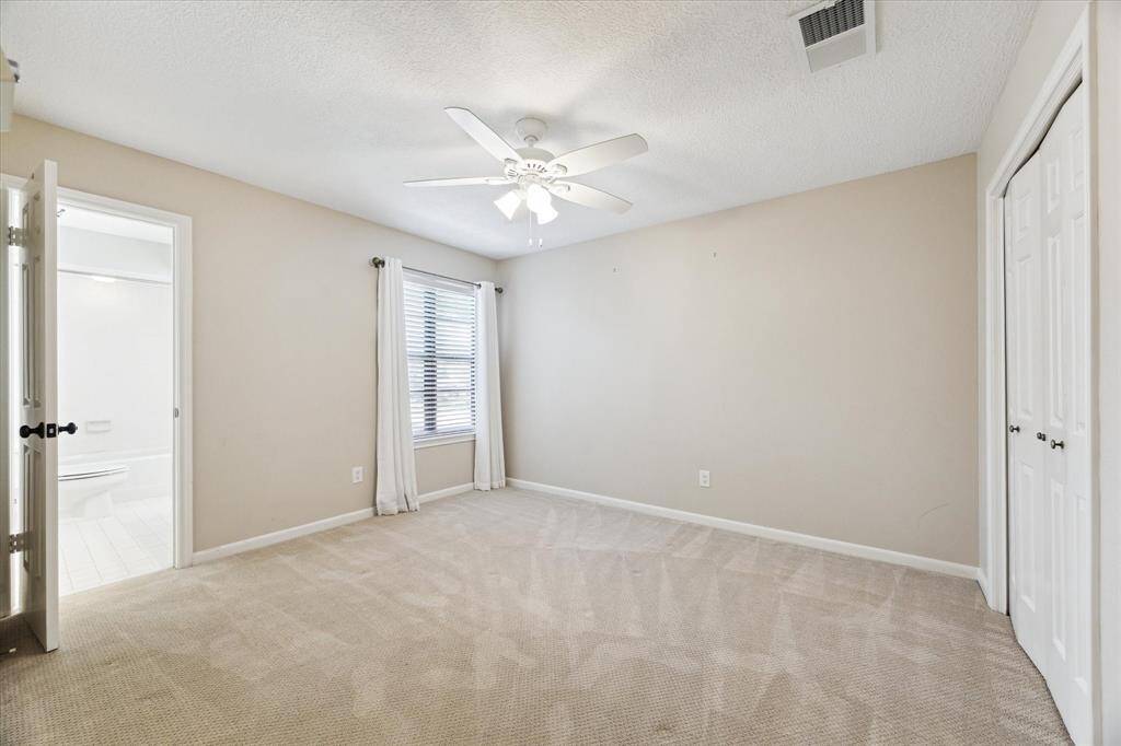 Upstairs bedroom with ceiling fan, ample closet space and view of front lawn.