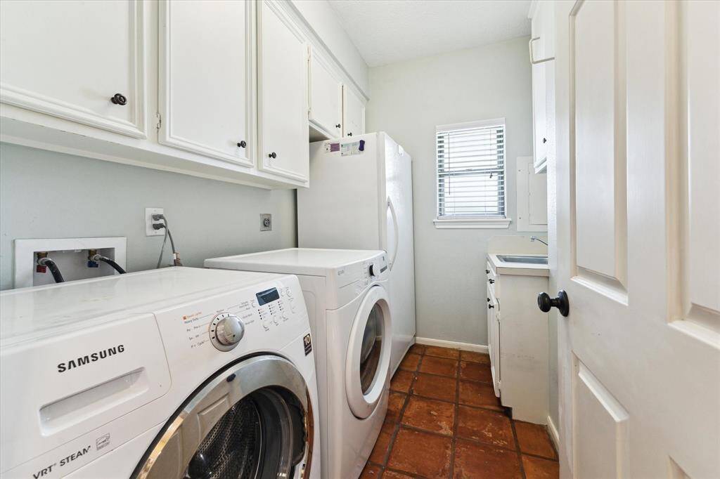 Utility room off of the kichen hosts the washer, dryer, handy storage, sink and extra freezer.