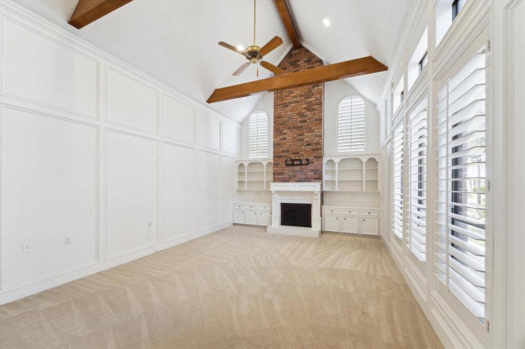 The expansive living room features a vaulted ceiling, ceiling fan, fireplace, and wonderful built-ins. It creates such a welcoming ambiance for any size gathering.