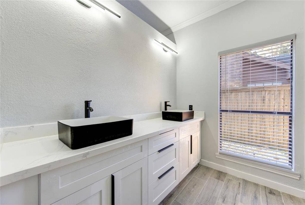 Elegant primary bathroom featuring dual black vessel sinks, sleek fixtures, and abundant natural light.
