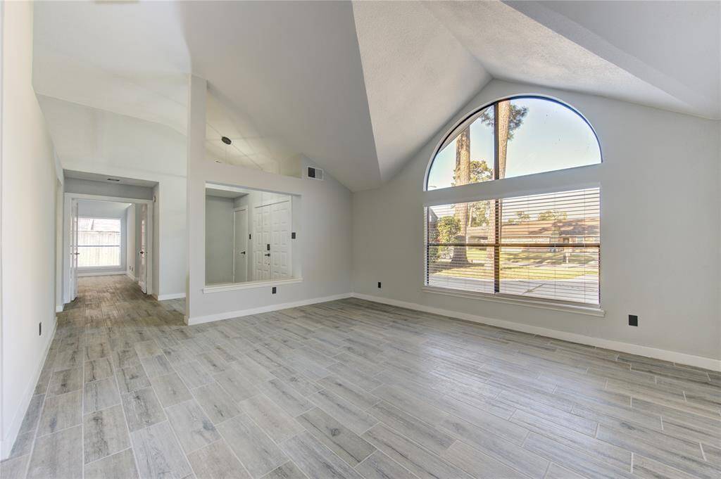 Bright and inviting front sitting area with vaulted ceilings and a large arched window, perfect for relaxation or entertaining.