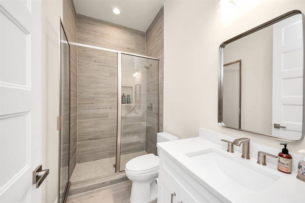 Conveniently located shared bathroom. This well-appointed bathroom, serving the secondary bedrooms, features a modern walk-in shower with sleek tile surround and a stylish vanity.  It offers a comfortable and functional space for everyday use.